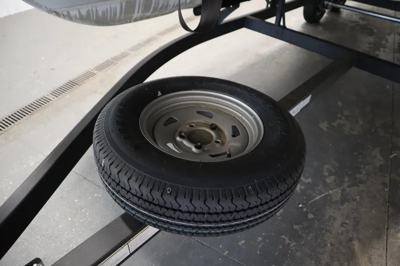 Slide: The Image of 2023 Tracker 20 DLX PARTY BARGE trailer tire on display in a garage setting. - 48