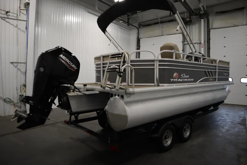 Slide: The Image of 2023 Tracker 20 DLX PARTY BARGE pontoon boat with Mercury outboard motor in a garage. - 5