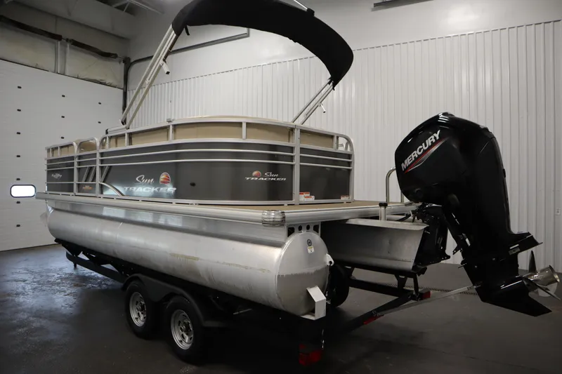 Slide: The Image of 2023 Tracker 20 DLX PARTY BARGE pontoon boat with Mercury outboard motor in a garage. - 7