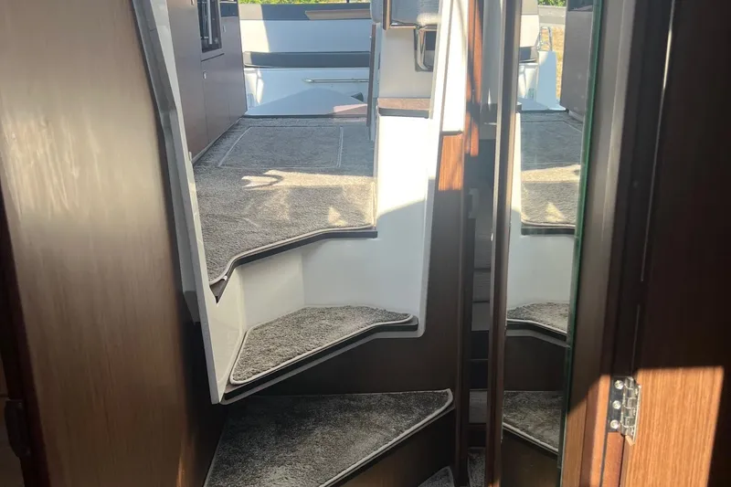 Slide: The Image of Interior view of 2023 Jeanneau NC Weekender 1095 with carpeted stairs and wooden accents. - 30