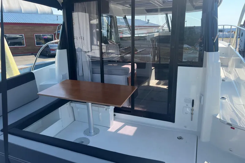 Slide: The Image of 2023 Jeanneau NC Weekender 1095 boat with outdoor seating and table, docked at marina. - 35