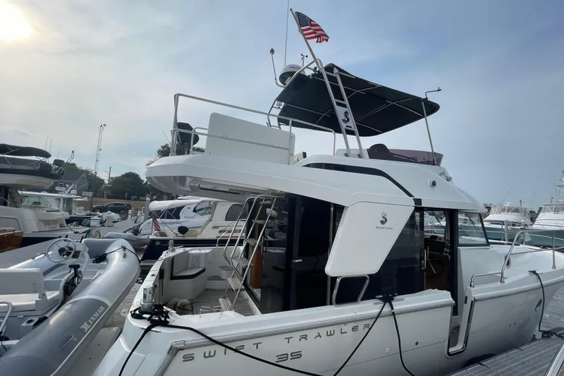 Slide: The Image of 2018 Beneteau Swift Trawler 35 docked, featuring upper deck and American flag. - 11