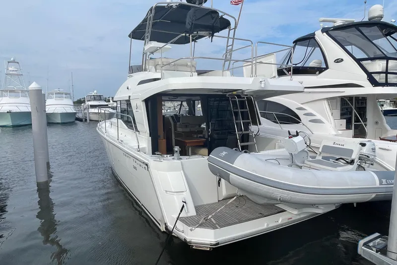 Slide: The Image of 2018 Beneteau Swift Trawler 35 docked, featuring a dinghy and spacious deck area. - 3