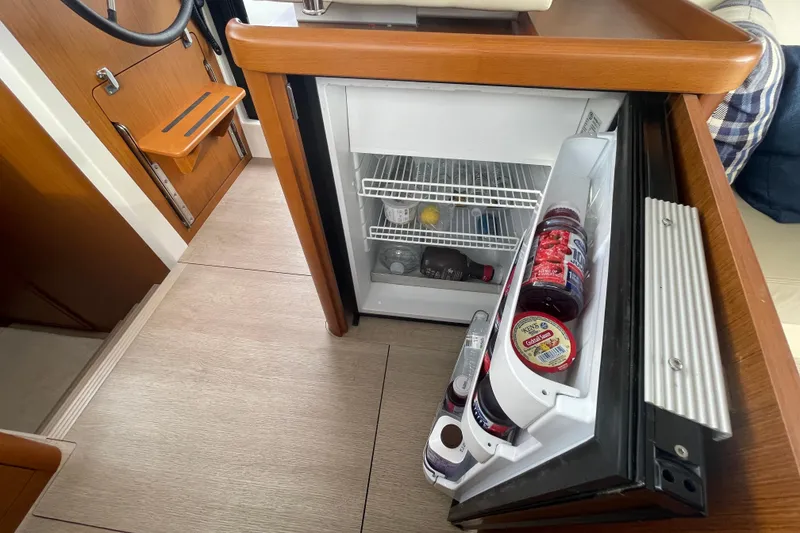 Slide: The Image of Interior of 2018 Beneteau Swift Trawler 35 with open mini fridge and wooden accents. - 32