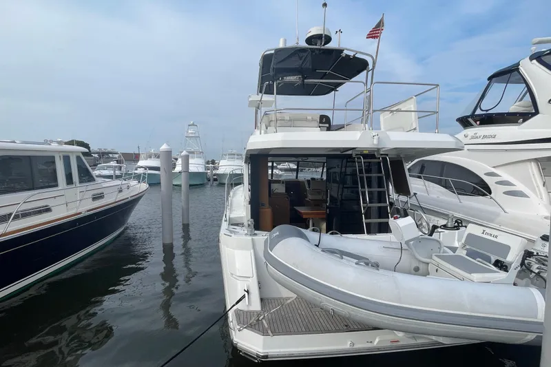 Slide: The Image of 2018 Beneteau Swift Trawler 35 docked, featuring a dinghy and spacious deck area. - 4