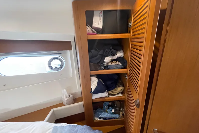 Slide: The Image of Wooden closet with clothes inside a 2018 Beneteau Swift Trawler 35 cabin. - 61