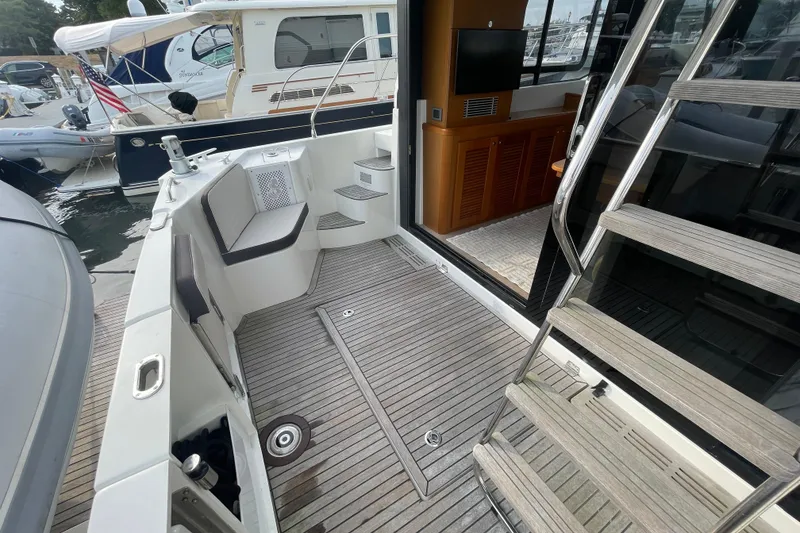 Slide: The Image of 2018 Beneteau Swift Trawler 35, spacious deck with seating and steps, docked at marina. - 73