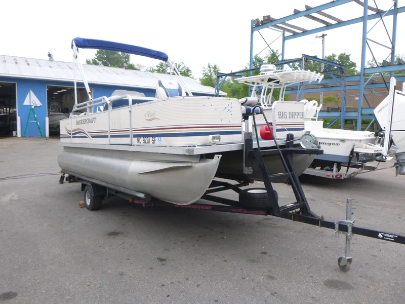 Slide: The Image of 2000 Smoker Craft 818 4-Point pontoon boat on trailer in a boatyard. - 3