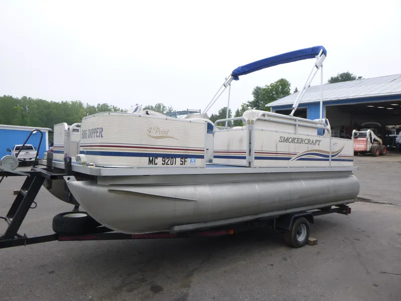 Slide: The Image of 2000 Smoker Craft 818 4-Point pontoon boat on trailer, parked outdoors. - 4