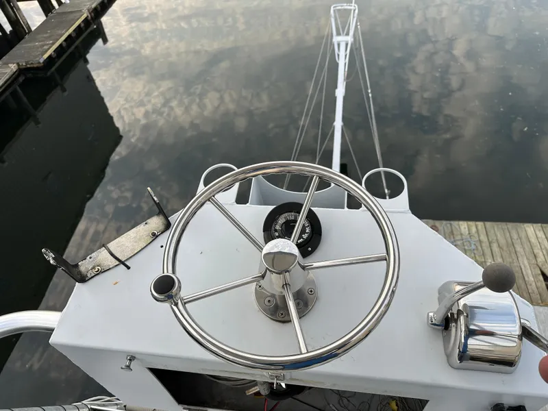 Slide: The Image of Steering wheel and controls of a 2003 BHM Sport Fish boat at a dock. - 13