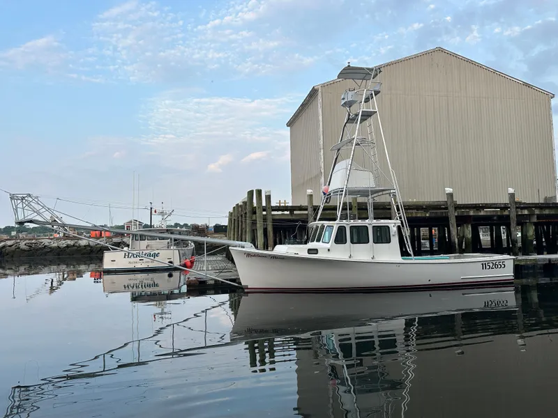 Slide: The Image of 2003 BHM Sport Fish boat docked by a pier, calm water reflection. - 2
