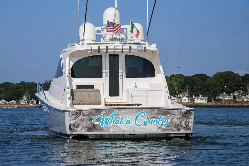 Slide: The Image of 2022 Viking 54 Sport Coupe yacht cruising on open water, creating dynamic wake patterns. - 14