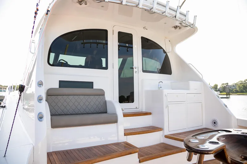 Slide: The Image of 2022 Viking 54 Sport Coupe yacht interior with seating and storage, overlooking serene waters. - 18