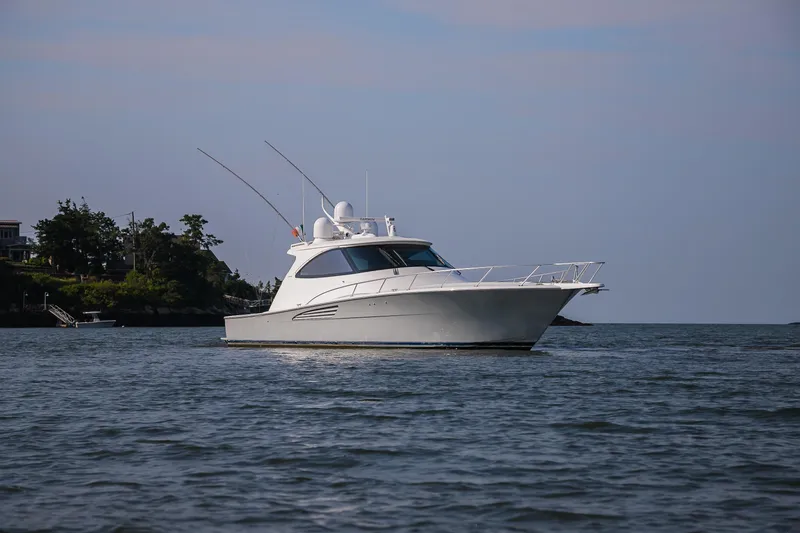 Slide: The Image of 2022 Viking 54 Sport Coupe cruising on open water under clear blue sky. - 5