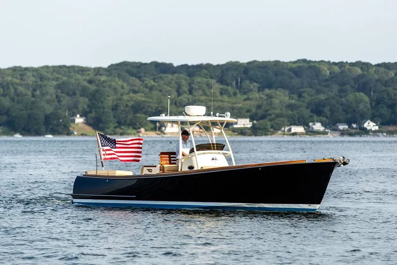 Slide: The Image of 2014 Hinckley T29 CC boat on water with American flag, forested shoreline in background. - 11