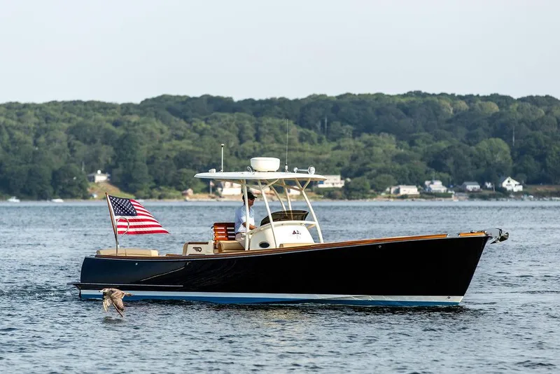 Slide: The Image of 2014 Hinckley T29 CC boat cruising on a serene lake with an American flag. - 12