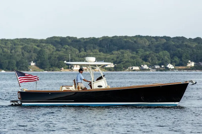 Slide: The Image of 2014 Hinckley T29 CC boat cruising on water with American flag, scenic background. - 13