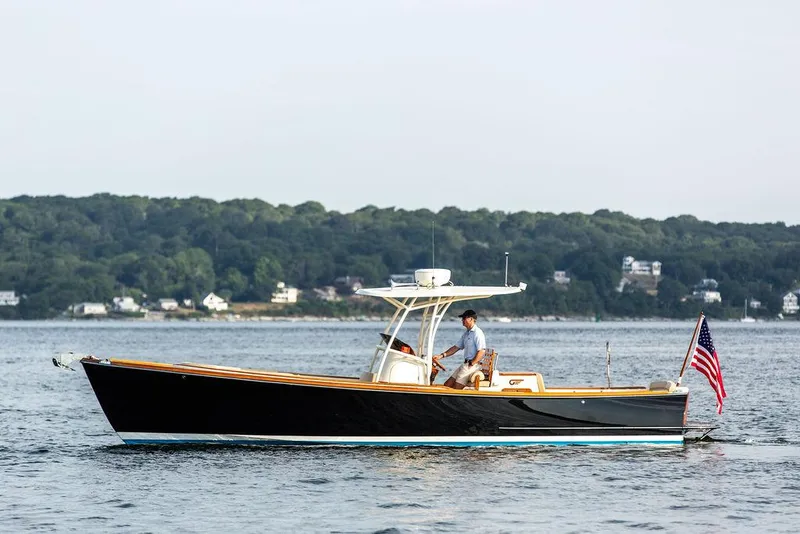 Slide: The Image of 2014 Hinckley T29 CC boat cruising on a calm lake with forested shoreline. - 5