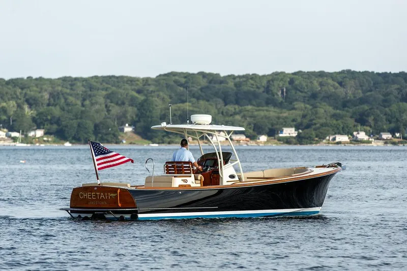 Slide: The Image of 2014 Hinckley T29 CC boat cruising on a calm lake with American flag. - 15