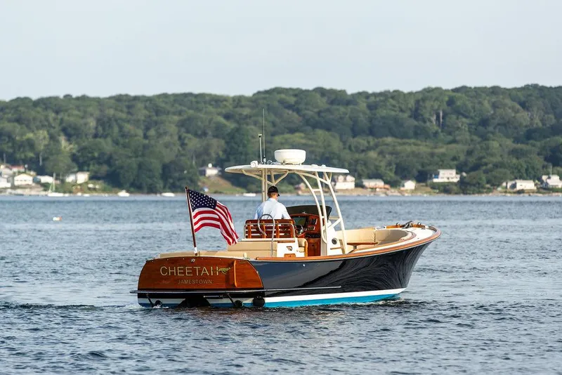 Slide: The Image of 2014 Hinckley T29 CC boat cruising on a scenic lake with American flag. - 16