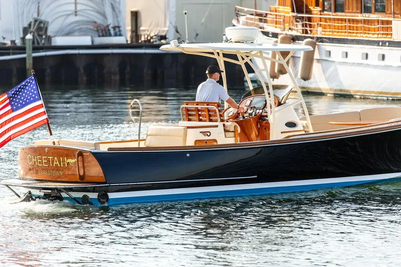 Slide: The Image of 2014 Hinckley T29 CC boat with American flag, cruising in a marina. - 27