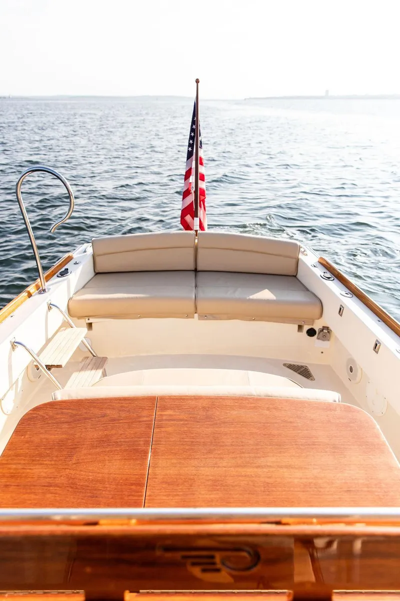 Slide: The Image of Hinckley T29 CC 2014 boat with American flag, wooden deck, and cushioned seating on open water. - 35