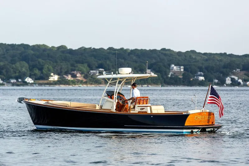 Slide: The Image of 2014 Hinckley T29 CC boat on calm water with American flag, scenic shoreline background. - 4