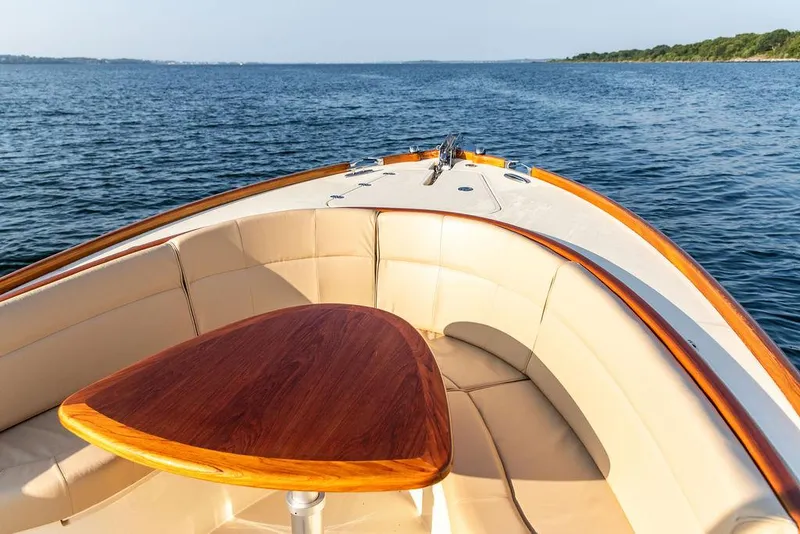 Slide: The Image of Hinckley T29 CC 2014 boat interior with wooden table and cushioned seating on open water. - 41