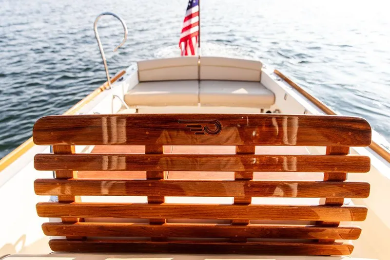 Slide: The Image of Hinckley T29 CC 2014 boat with wooden seating and American flag on calm water. - 45