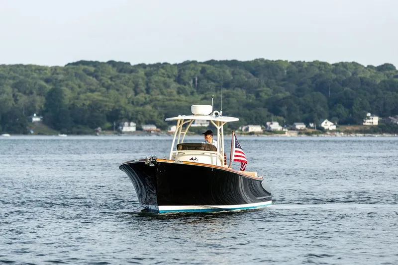 Slide: The Image of 2014 Hinckley T29 CC boat cruising on a scenic lake with forested shoreline. - 8