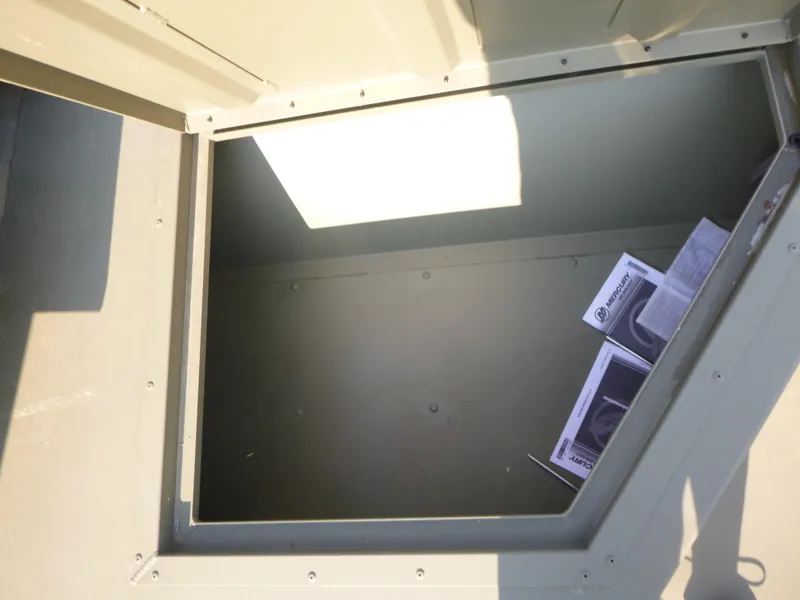 Slide: The Image of Open storage compartment in 2024 Tracker Grizzly 2072 CC Sportsman boat, with manuals inside. - 10