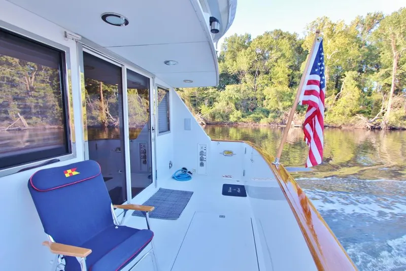 Slide: The Image of 1992 Tollycraft 53 Motor Yacht deck with American flag and chair, cruising on a calm river. - 18