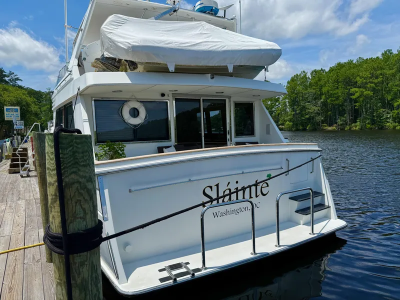Slide: The Image of 1992 Tollycraft 53 Motor Yacht docked by a serene river with lush greenery. - 3