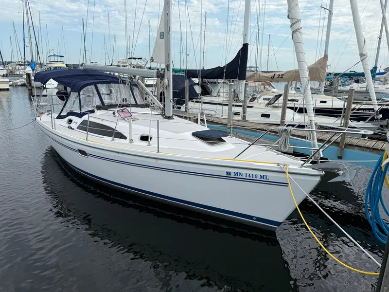 Slide: The Image of 2007 Catalina 309 sailboat docked in marina, featuring sleek design and blue canopy. - 2