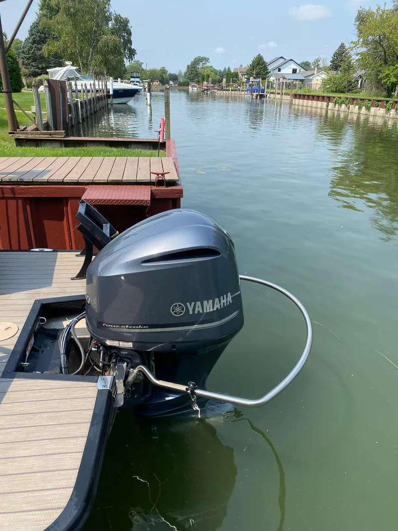 Slide: The Image of Outboard motor on a 2018 Bennington 25 GCW pontoon boat docked by a scenic canal. - 11