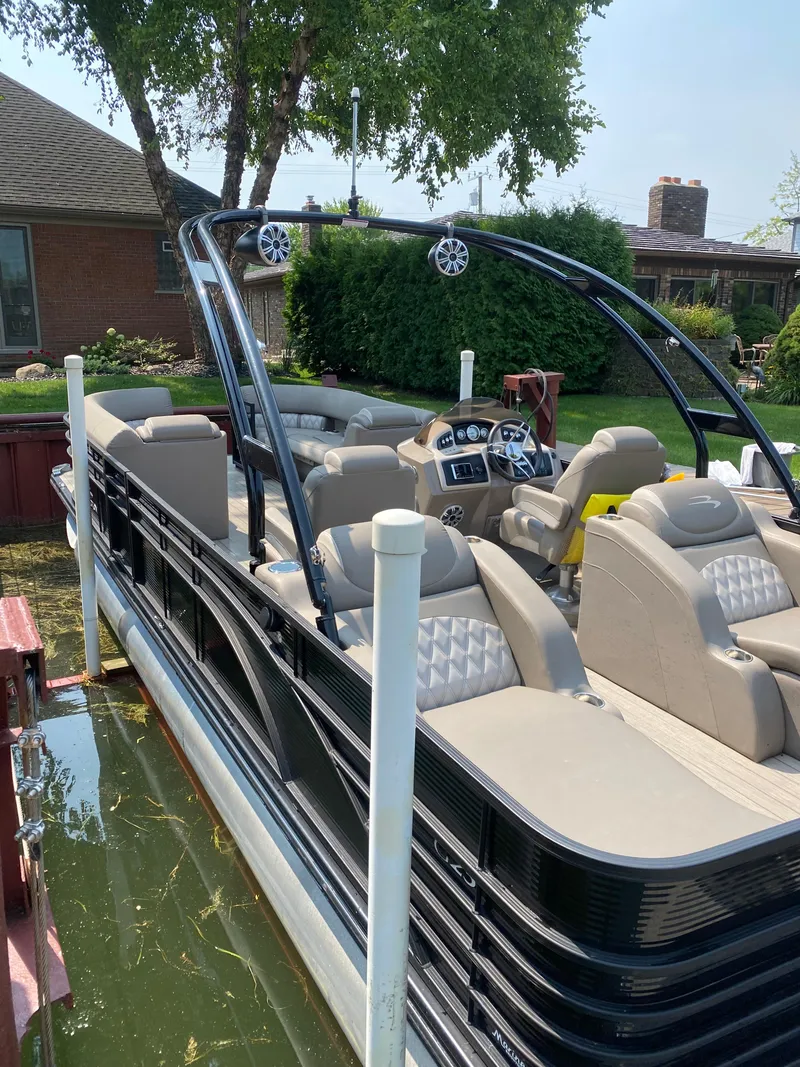 Slide: The Image of 2018 Bennington 25 GCW pontoon boat docked near a house, featuring luxurious seating. - 2