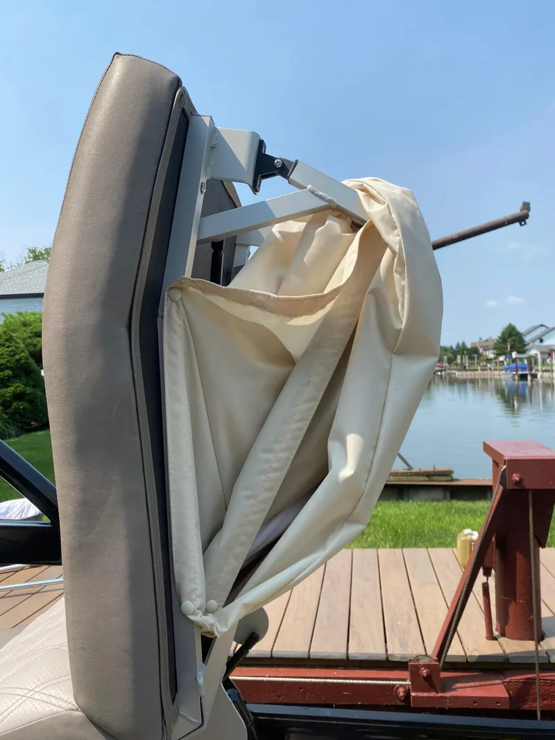 Slide: The Image of 2018 Bennington 25 GCW boat seat with folded canopy by a lakeside dock. - 27