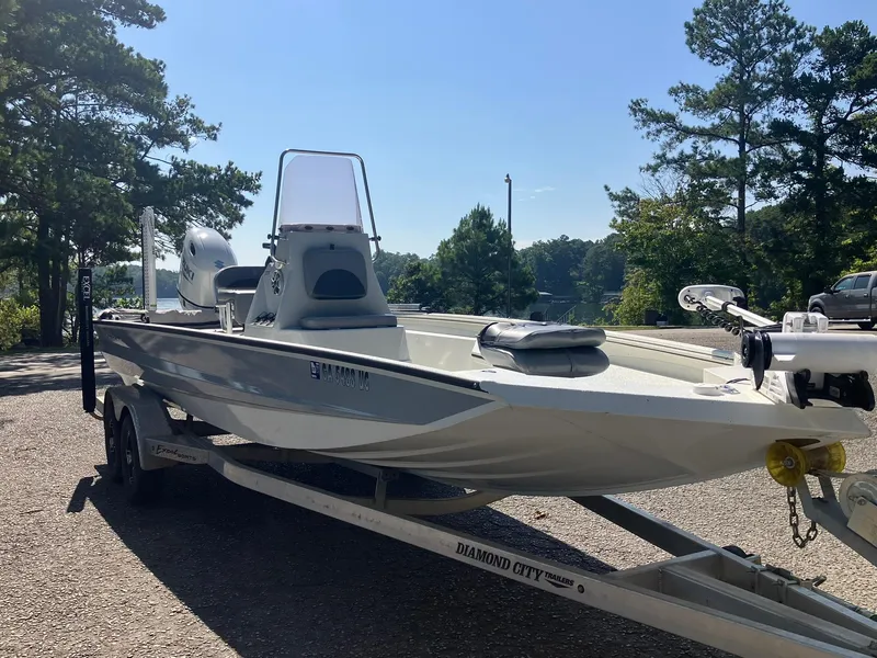 Slide: The Image of 2022 Excel 220 Bay Pro boat on trailer, parked near trees and water. - 17