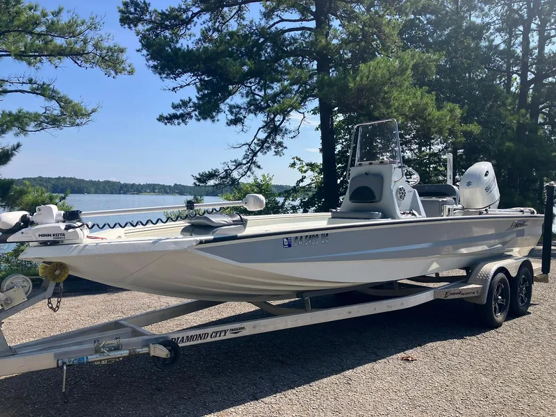 Slide: The Image of 2022 Excel 220 Bay Pro boat on trailer by a lake, surrounded by trees. - 3