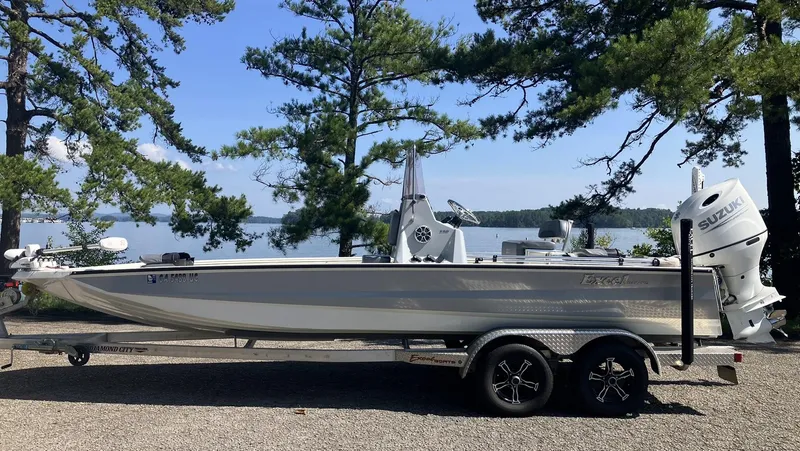 Slide: The Image of 2022 Excel 220 Bay Pro boat on trailer by lake, surrounded by trees. - 4