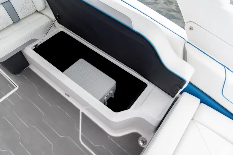 Slide: The Image of 2026 Regal LS9 Surf boat storage compartment with cooler, featuring sleek white and blue interior design. - 14