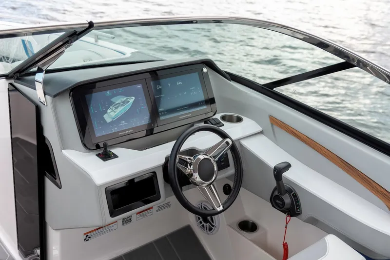Slide: The Image of 2026 Regal LS9 Surf boat dashboard with dual screens and steering wheel, overlooking water. - 19