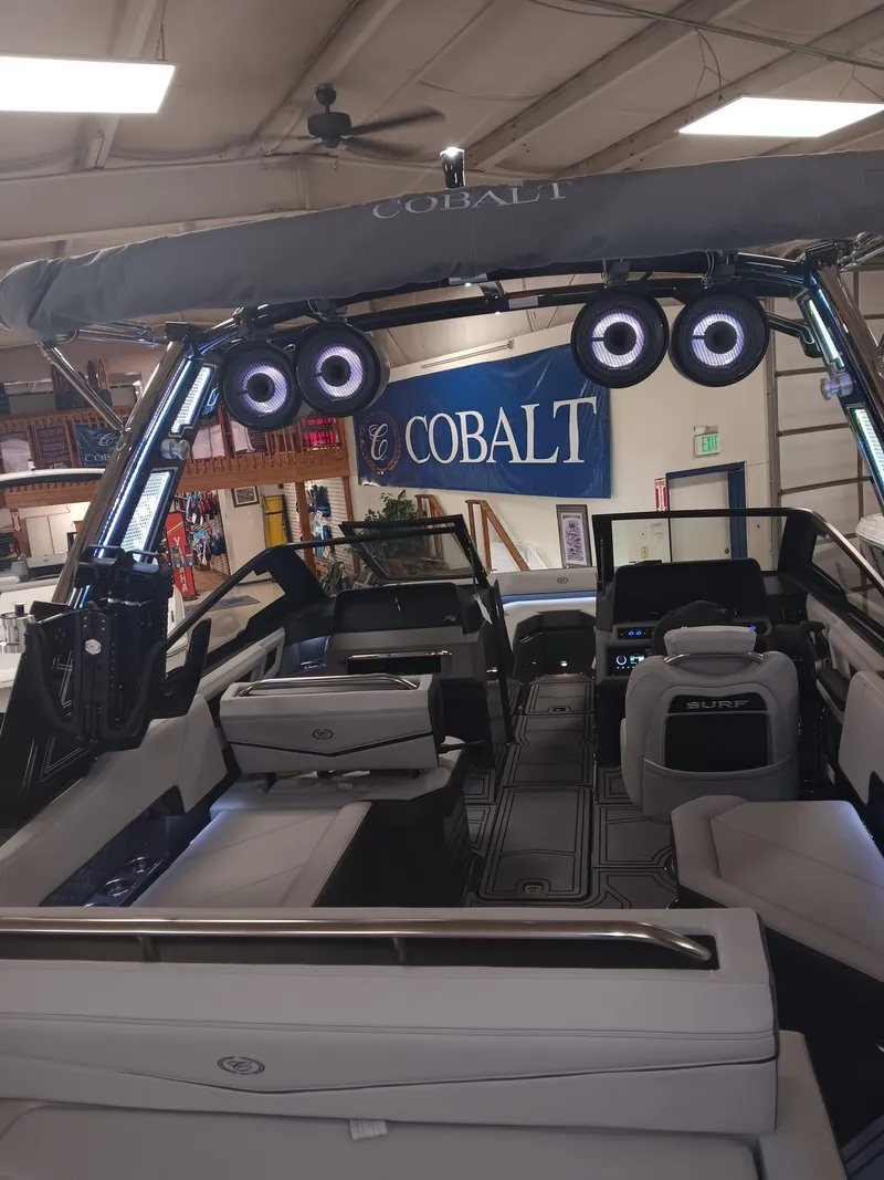 Slide: The Image of 2026 Cobalt R4 Surf boat interior with advanced audio system and sleek design in showroom. - 11