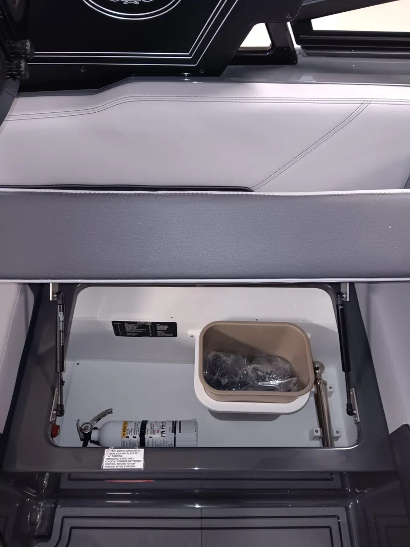 Slide: The Image of 2026 Cobalt R4 Surf boat storage compartment with fire extinguisher and container. - 16