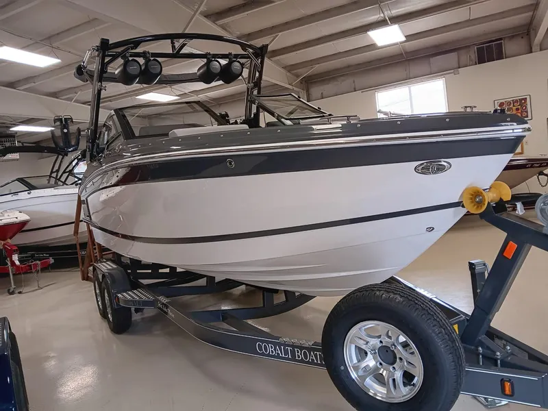 Slide: The Image of 2026 Cobalt R4 Surf boat on trailer in showroom, featuring sleek design and modern features. - 2