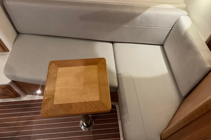 Slide: The Image of 2026 Back Cove 39O boat interior with striped seating and wooden table. - 10