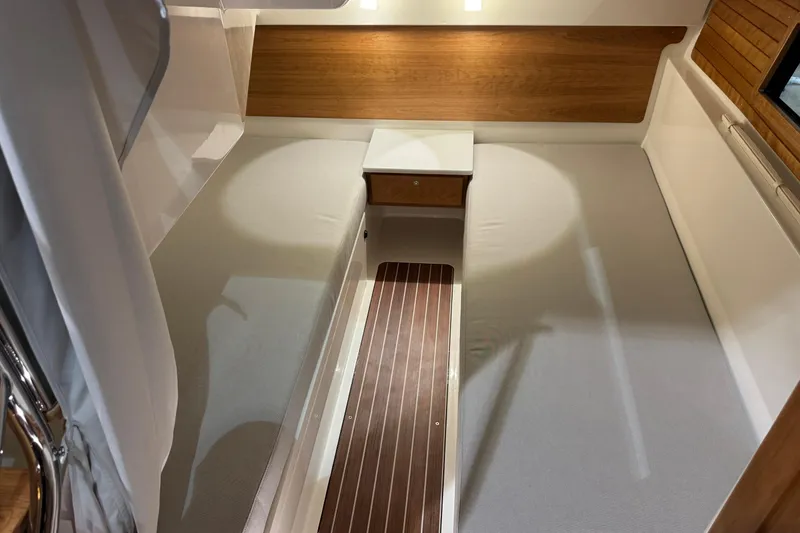 Slide: The Image of 2026 Back Cove 39O boat interior with striped seating and wooden table in a showroom. - 13
