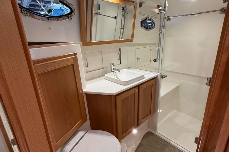 Slide: The Image of 2026 Back Cove 39O boat interior with striped seating and wooden table. - 14