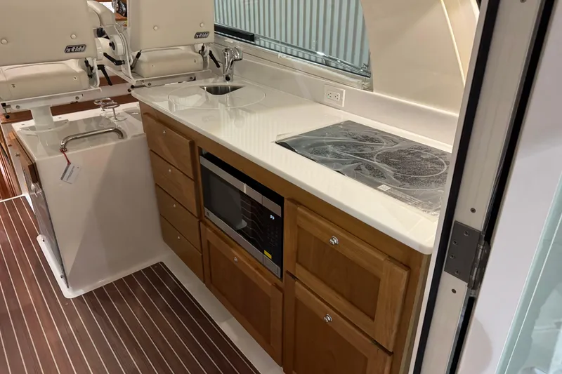Slide: The Image of 2026 Back Cove 39O yacht interior with kitchenette, featuring wooden cabinets, sink, and microwave. - 20