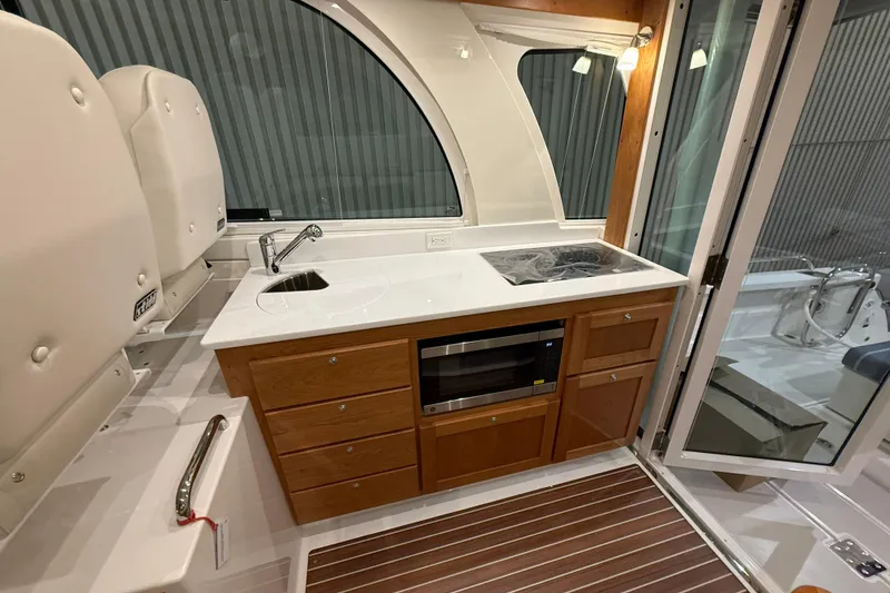 Slide: The Image of 2026 Back Cove 39O yacht interior with kitchenette, featuring sink, stove, and wooden cabinetry. - 21